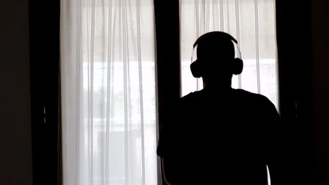 Man in front of the window dances with headphones. shot from back Stock Footage 125530052
