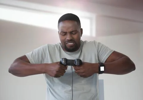 Man frustrated playing with computer game controller with bright background Stock Photos