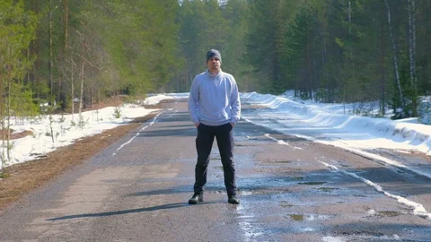 Man in full growth in cap in forest standing on country road looking at camera. Video stock 129596961