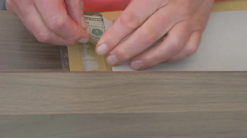 Man furtively checking a packet under a desk shelf with dollars inside. Video stock 138869405