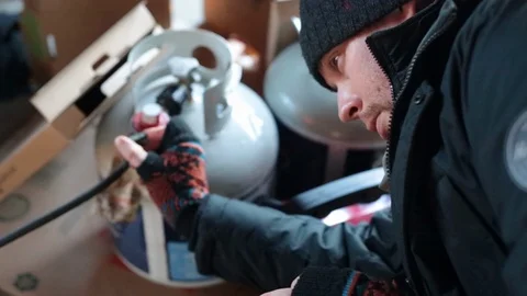 Man in garage adjust dial on propane tank flowing into cooker boiling a turkey Stock Footage 99597597