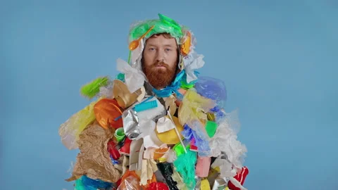 Man in the garbage costume looking at the camera. Different trash flying on him. Stock Footage 147178586