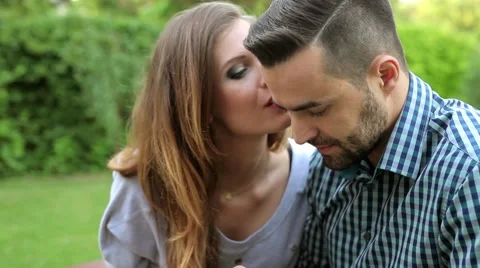 Man in garden is using phone and woman is kissing him Video stock 51440839