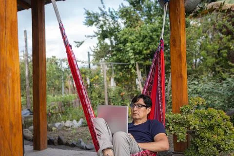 Man in a garden working in a hammock Foto stock