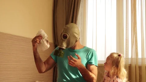 A man in a gas mask changes dirty diapers. Young father and child. Stock Footage 98726551