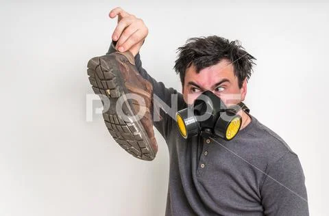 Man with gas mask is holding dirty stinky shoe Stock Photos
