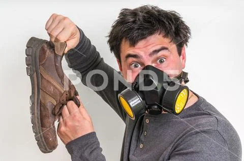Man with gas mask is holding dirty stinky shoe Stock Photos