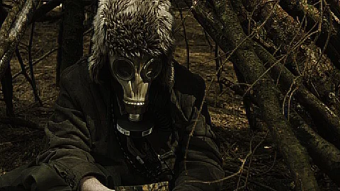 A man with a gas mask on sitting inside a small makeshift hut with a music box. Video stock 89407504