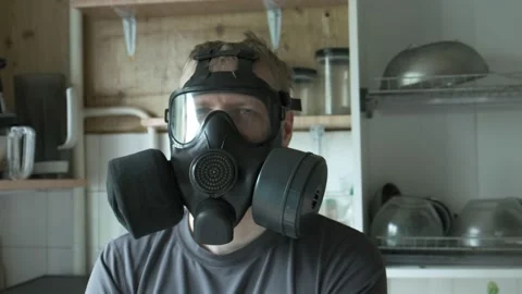 Man in gas mask sitting at kitchen at home. chemical weapon, virus protection Vídeos de archivo 136041035