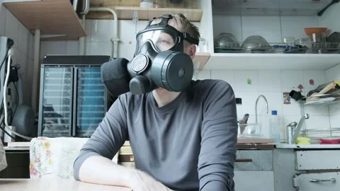 Man in gas mask sitting at kitchen at home. chemical weapon, virus protection Vídeos de archivo 136042371