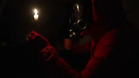 A man in a gas mask using a paraffin candle. electricity is out, bomb shelter 스톡 동영상 220482457