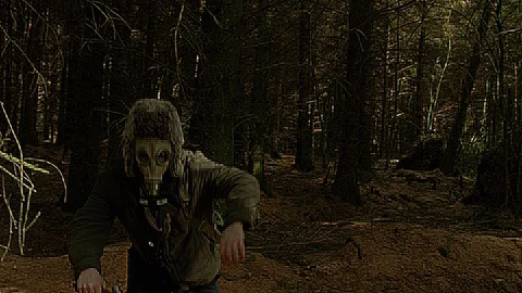 A man with a gas mask on walking through a dense forest. Video stock 89407561