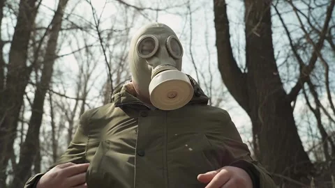 Man in gasmask.he pulls a smartphone from his jacket pocket and looks into it Stock Footage 130411161