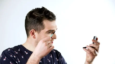 A man gay does makeup. He is combing his eyebrows. 4k Stock Footage 102068445