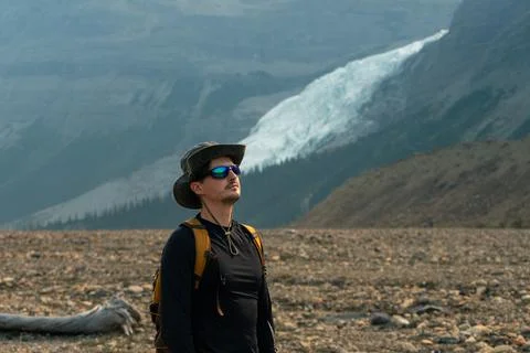 A man gazes up at the distant glacier, taking in the vast mountain range. Stock Photos