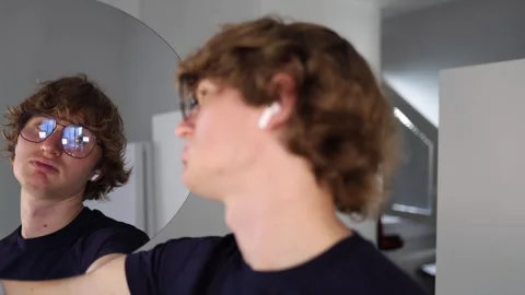 Man gazes at his reflection with a dramatic expression slightly tilted head and  Stock Footage 312981840