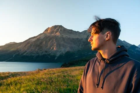 Man gazes towards distant mountain, illuminated by a warm sunset glow. Stock Photos