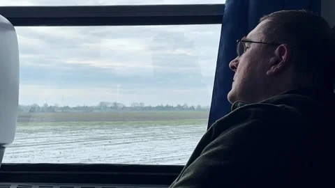 Man Gazing Out Train Window During Winter Scenic Journey Stockbeeldmateriaal 297702794