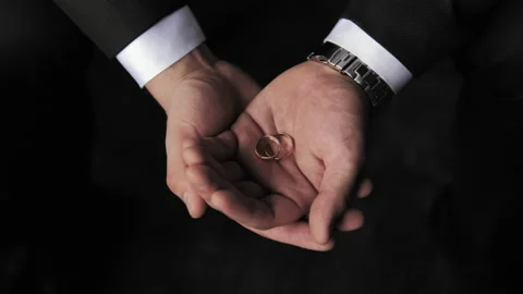 The man gently and slowly squeezes the wedding rings in his hands. Stock Footage 201013209