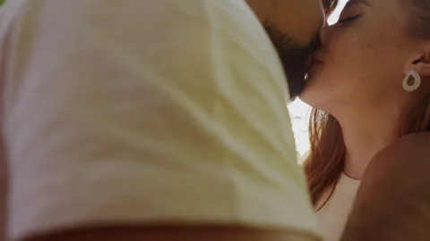Man gently caressing his girlfriend as they kiss in the breathtaking summer Stock Footage 248174243