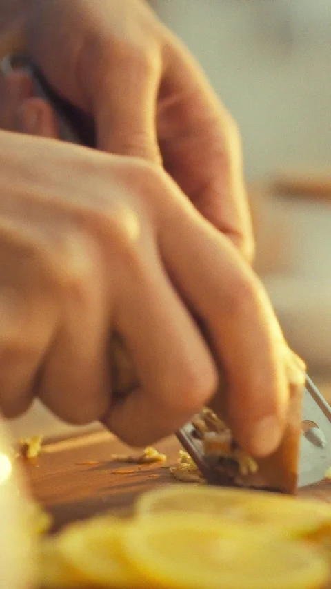 A man gently grates a fresh brown ginger root with a grater releasing its sh Stock Footage 334396012