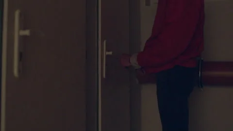 Man gently manipulates door handle during late evening in hallway Stock-Footage 322923936
