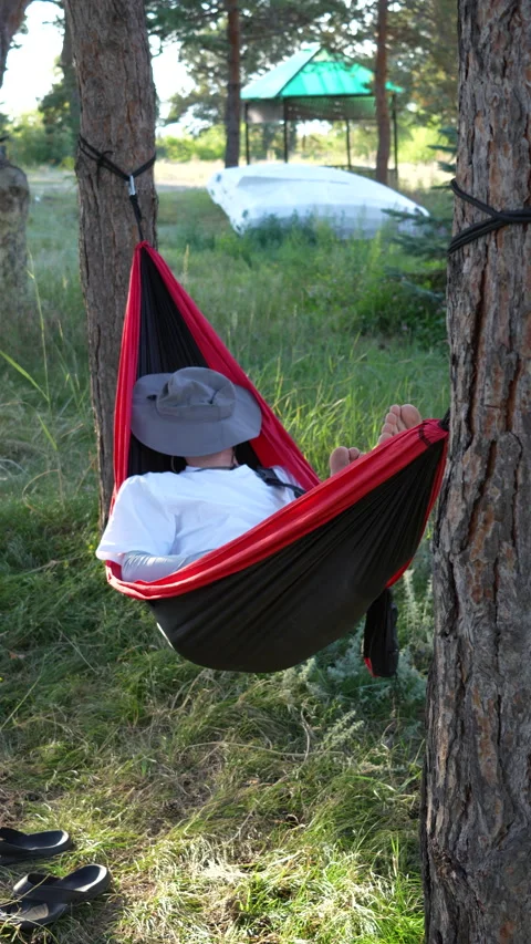 Man gently swinging in a hammock outdoors, 4K vertical Stock Footage 342027608