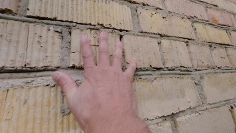 The man gently touches the brick wall with his hand. From the first person. 動画素材 342422023
