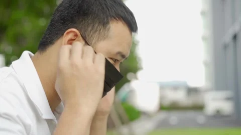 A man gently wearing mask while working in an open area 動画素材 145887249