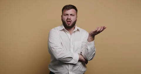 Man gestures with confused expression while standing against a yellow backg.. 動画素材 326797469