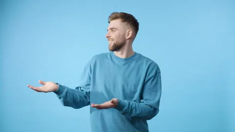 Man gestures with open palms against blue background Video stock 279480957