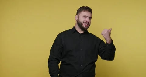 Man gestures with right hand while standing against a yellow background 스톡 동영상 326789257