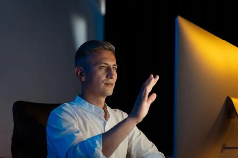 Man Gesturing at Computer Screen in Dark Office Setting Stock Photos