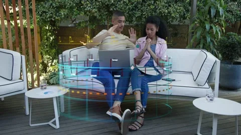 Man gesturing over laptop and woman tapping phone, manipulating AR interface for Stock Footage 333255671