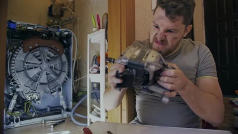 A man gets angry when he fixes a washing machine at home Stock Footage 155644397