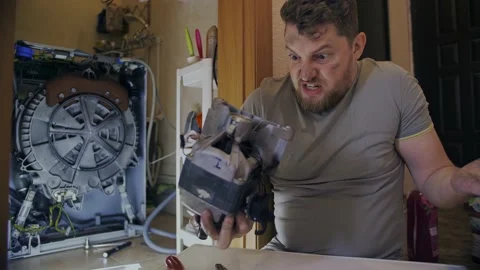 A man gets angry when he fixes a washing machine at home Stock Footage 155645142