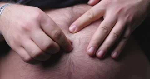 Man gets belly button lint out of his hairy belly button in 4k closeup Stockbeeldmateriaal 145016241
