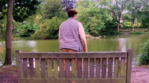 Man gets up from bench in slow motion. Leaves to right. Stock Footage 41762512