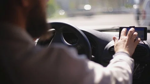 A man gets into the car and turns on the navigator on the smartphone Stock Footage 75448874