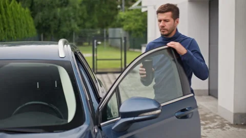 Man gets in car with coffee before driving to work Stock Footage 340489970