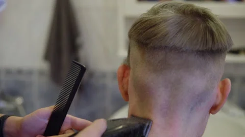 A man gets his hair cut in a barber shop. Hair clipper cuts hair Stock Footage