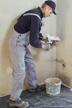 Man gets manually gypsum plaster Stock Photos