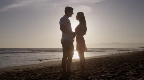 Man gets on one knee and puts ring on womans finger on sunset-lit beach in 4K Stock-Footage 39966522