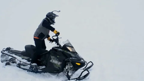 Man gets up on one side of a snowmobile and accelerates Stock-Footage 102212504