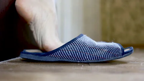 A man gets out of bed in the morning and puts on slippers. Stock Footage 140251642