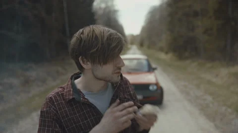 Man gets out of the car and lights up the cigarette Stock Footage 63333332