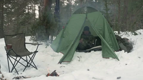 A man gets out of a tent in a winter camp in the forest. Video stock 170157355