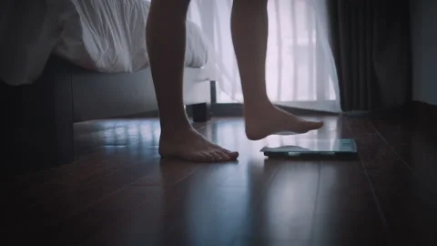 A man gets on the scales immediately after waking up, morning weigh-in Stock Footage 314506260