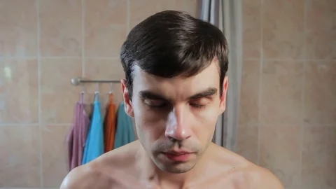 Man gets shaving foam on the face. The guy starts to shave in front of a mirror Video stock 81691369