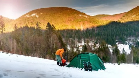 Man gets something out of backpack near the tent on snow Stock Photos